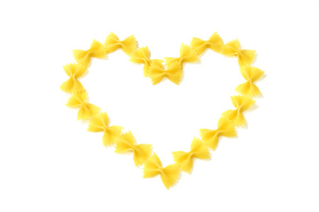 Closeup of italian pasta  a heart shape, farfalle isolated on white  background