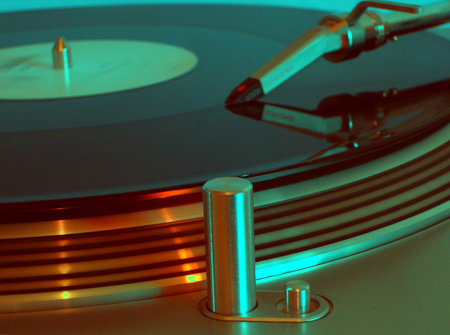 Closeup of a spinning record on a turntabe in a club. the highlights are orange and blue