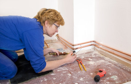 female plumber soldering copper pipes on a construction siteの写真素材