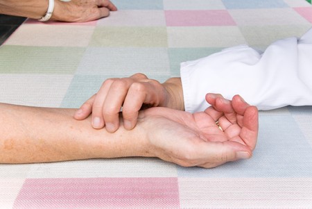 hand of a physician, measuring the pulse rate of a senior patientの写真素材