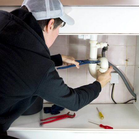 plumber fixing a broken drain pipe in the kitchen
