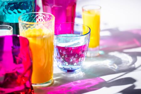 Glass goblets create wonderful coloured shadows on a solar table. The shadow of sunlight reflect to glass of pink and yellow, emerald colorsの写真素材