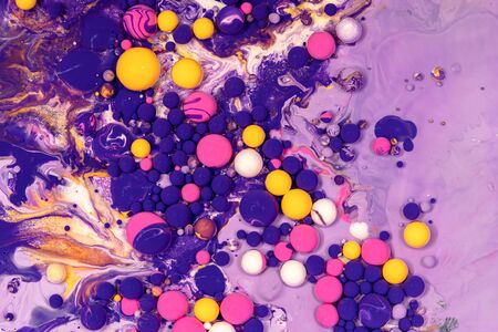 Acrylic paint balls abstract texture. Purple, blue, pink and yellow liquids mix. Creative multicolor background. Bright colors fluid, flowing wallpaper design. Mixed pigments violet backdropの写真素材