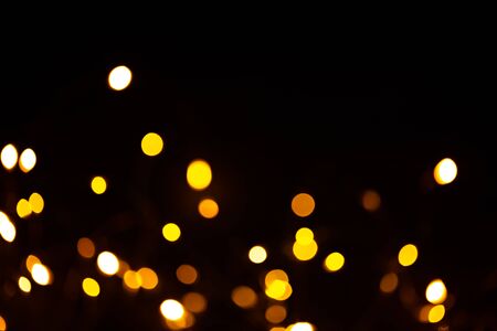 Golden sparkles raster festive background. Bokeh lights with bright shiny effect illustration. Overlapping glowing and twinkling spots decorative backdrop. Abstract glittering circlesの写真素材