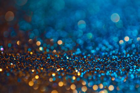 Festive twinkle glitters background, abstract glowing backdrop with circles,modern design wallpaper with sparkling glimmers. Blue and golden backdrop glittering sparks with glow effectの写真素材