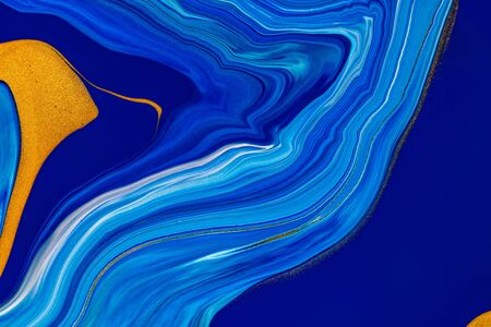 Fluid art texture. Abstract backdrop with iridescent paint effect. Liquid acrylic artwork that flows and splashes. Classic blue color of the year 2020. Blue, golden and white overflowing colorsの写真素材