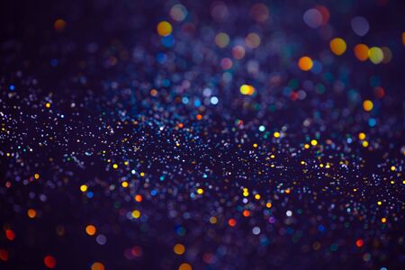 Decoration bokeh glitters background, abstract blurred backdrop with circles,modern design overlay with sparkling glimmers. Blue, purple and golden backdrop glittering sparks with glow effectの写真素材