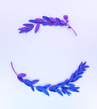 Creative neon background with leaves. Colorful abstract backdrop with frame of plants and space for text. Exotic nature branch with blue and purple vivid colors. Organic twigs with shiny illuminationの写真素材