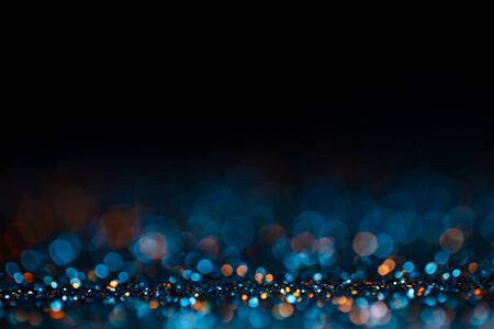Decoration twinkle glitters background, abstract shiny backdrop with circles,modern design wallpaper with sparkling glimmers. Black, blue and golden backdrop glittering sparks with blur effectの写真素材