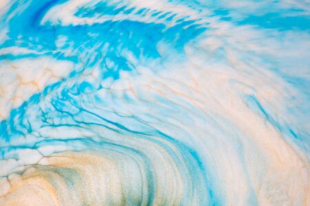 Fluid art texture. Backdrop with abstract swirling paint effect. Liquid acrylic picture with flows and splashes. Mixed paints for baner or wallpaper. Blue, golden and white overflowing colorsの写真素材