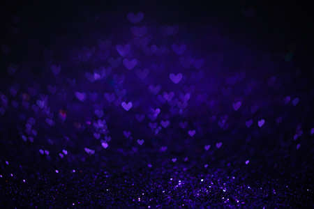 Festive twinkle glitters background, abstract sparkle backdrop with hearts, modern design overlay with sparkling glimmers. Purple, blue and black backdrop glittering sparks with glow effectの写真素材
