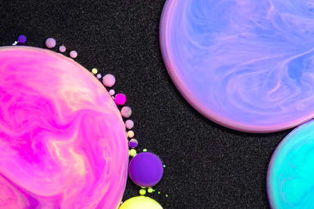 Fluid art texture. Background with abstract iridescent paint effect. Liquid acrylic artwork that flowing bubbles. Mixed paints for background or poster. Black and neon overflowing colorsの写真素材