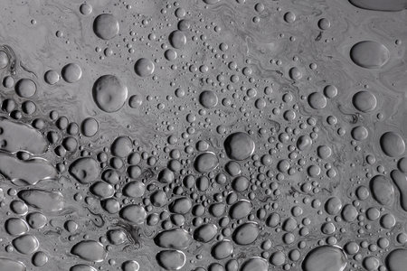Fluid art moon texture. Abstract background with swirling paint effect. Liquid acrylic artwork with flowing bubbles. Mixed paints for background or poster. Black, white and gray overflowing colorsの写真素材