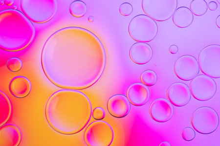 Creative neon background with drops. Glowing abstract backdrop with vibrant gradients on bubbles. Lilac, orange and pink overflowing colors.の写真素材