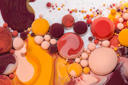 Fluid art texture. Abstract backdrop with mixing paint effect. Liquid acrylic picture with flowing bubbles. Mixed paints for background or poster. Yellow, coral, orange and brown overflowing colorsの写真素材