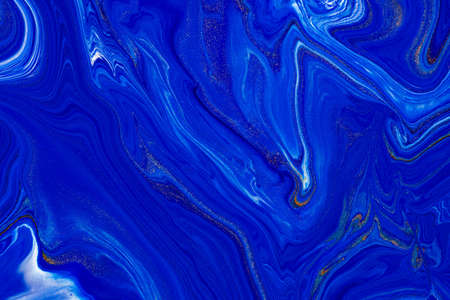 Fluid art texture. Abstract backdrop with swirling paint effect. Liquid acrylic artwork that flows and splashes. Classic blue color of the year 2020. Blue, golden and white overflowing colorsの写真素材