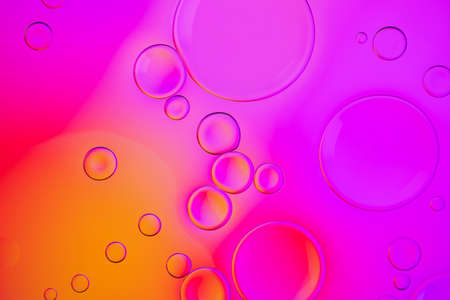 Creative neon background with drops. Glowing abstract backdrop with vibrant gradients on bubbles. Purple, red and orange overflowing colors.の写真素材
