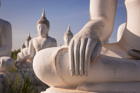 Hand of  white buddha status on blue sky background in thailandの写真素材