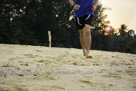 Barefooted man running on the Beach at Sunsetの写真素材