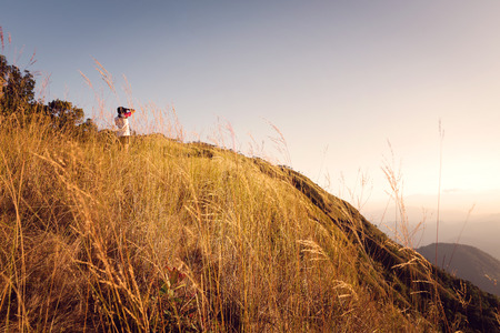 Beautiful grass flowers with mountain and bright sun shining on the sky at Doi Tu Lay Mon Tu Lay , Tak province Thailandの写真素材