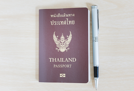 Thailand passport and a pen on wooden backgroundの写真素材