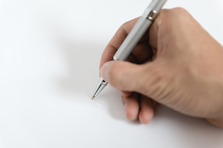 Close up of man hand writing with metallic pen on white backgroundの写真素材