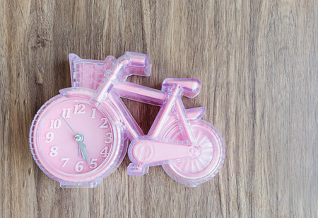 pink plastic bicycle clock on a wooden background