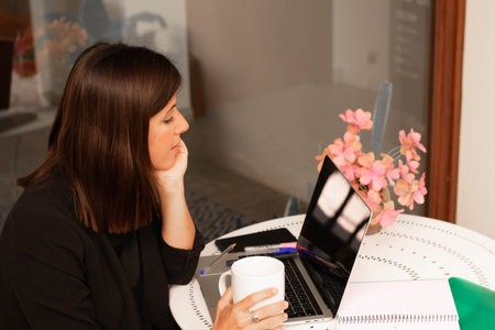 young woman working at home using laptop and having a call
