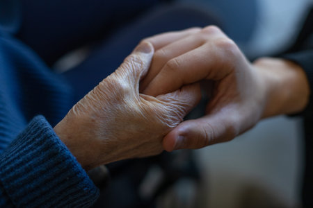 Close-up of an elderly woman holding hands with her caregiver