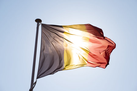 Belgium flag waving in the wind on blue sky background.