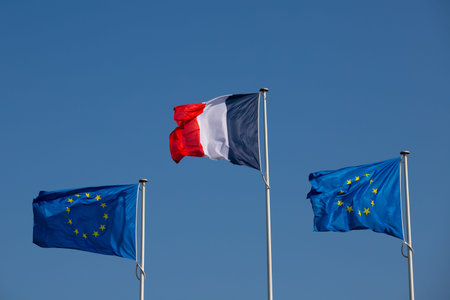 European Union and France flags waving in the wind on blue sky background