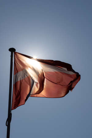 Flag of the Latvian Republic waving in the wind against the blue skyの写真素材