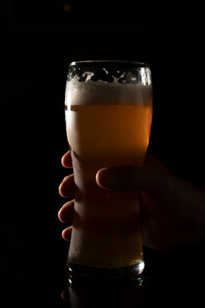 hand holding glass of beer on black backgroundの写真素材