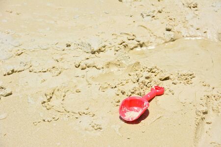 Red plastic shovel toy on the beachの写真素材