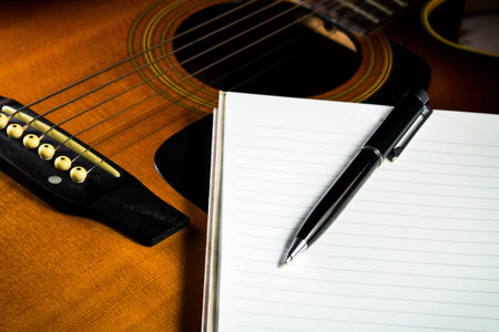 Notebook and pen on acoustic guitar