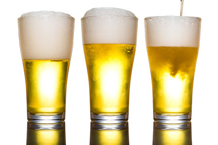 Beer with foam in glass isolated on whiteの写真素材