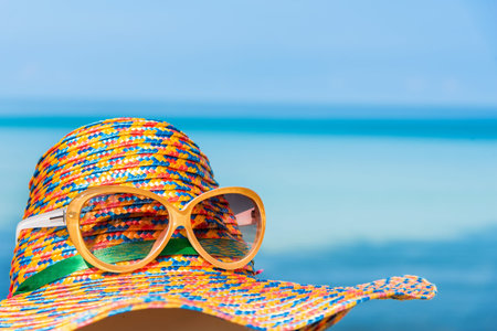 Sunglasses and straw hat with blur blue sea and sky background - holiday conceptの写真素材
