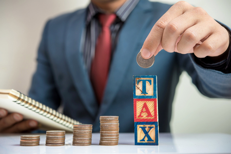 TAX word and step of coins with businessman backgroundの写真素材