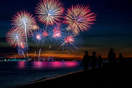 Amazing beautiful colorful fireworks display on celebration night, showing on the sea beach with multi color of reflection on waterの写真素材