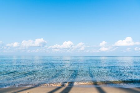 Tropical beautiful beach sand and sea with wave reaching shore with blue sky and white clouds, summer travel or vacation conceptの写真素材