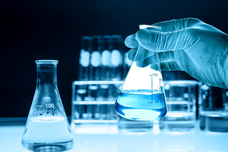 hand of scientist holding flask with lab glassware in chemical laboratory background, science...