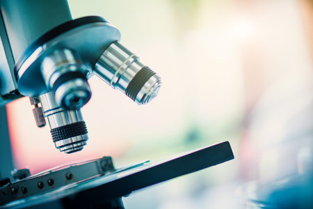 Microscope with lab glassware and dropping chemical liquid to test tube in chemical laboratory...