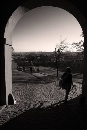 Woman walks through an arc, on a paved street in Praguesの写真素材