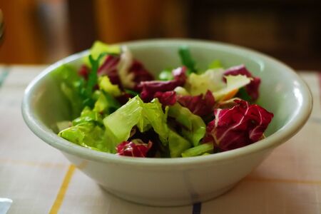 Green and red salad bowl on a traditional italian tableの写真素材