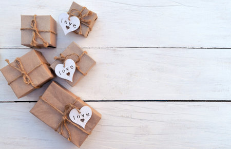 Gift boxes with hearts hand made on a light wooden background. Celebratory background. Christmas New...