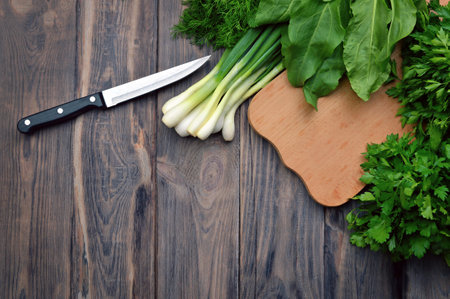 Dill, spinach, sorrel, coriander, parsley, green onion on a cutting board. Fresh greens on a wooden background. Flat-lay. Food background. The concept of healthy eating.の写真素材