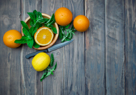 Preparation of summer refreshing fruit drinks. Citrus and aromatic herbs on a wooden table. The concept of a healthy diet and detoxification. Vitamins.の写真素材