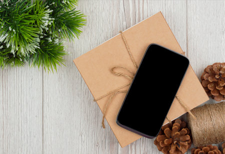 Christmas shopping online. Mockup, blank screen smartphone on wood background for Christmas and New Year concept, Flat lay. top view, copy space.の写真素材