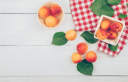 ripe apricots on a wooden background with green leaves. fresh farm apricot harvest. sweet delicious apricots. Top view. Flat lay.の写真素材