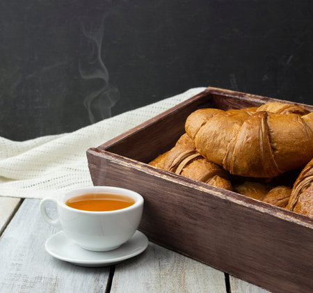 Breakfast with tea and croissants. freshly baked croissant. concept production of croissants. Freshly Buttery baked croissants. French and American Croissants and Baked Pastries are enjoyed worldwide.の写真素材